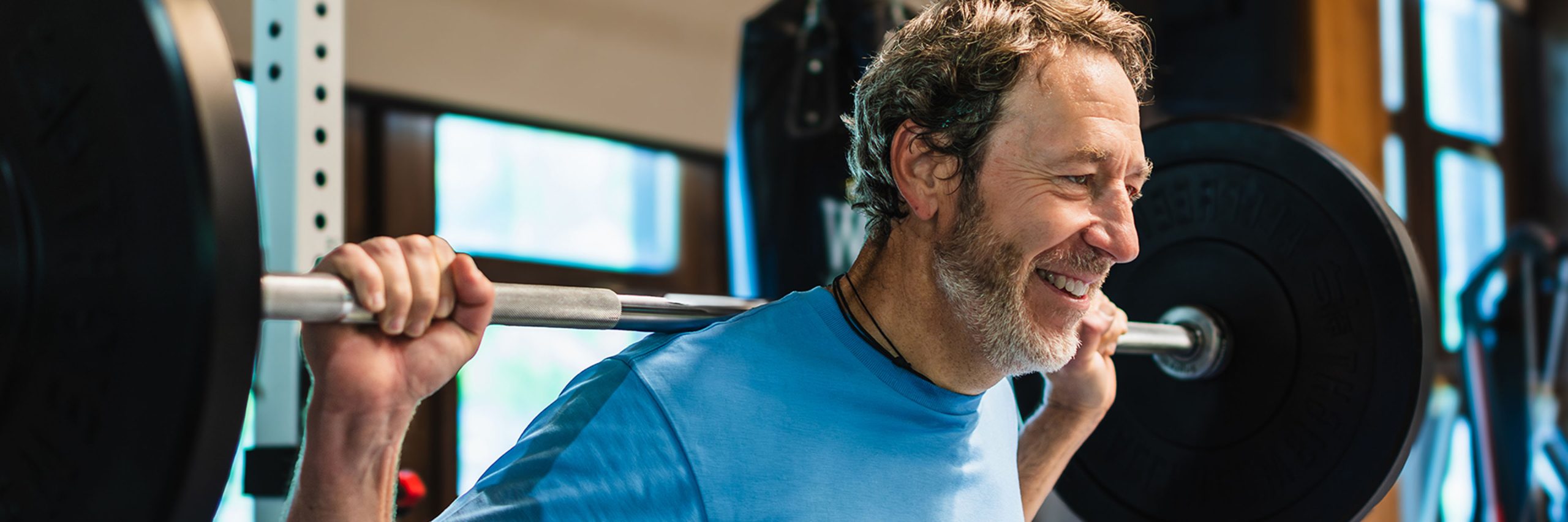 Man lifting weights, smiling happily.